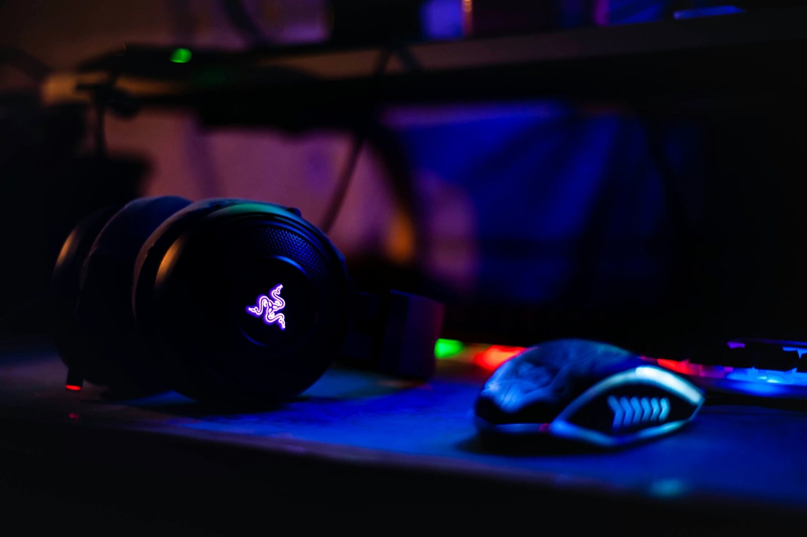 Image of an headphone and mouse meant for gaming. Dark image with colors.